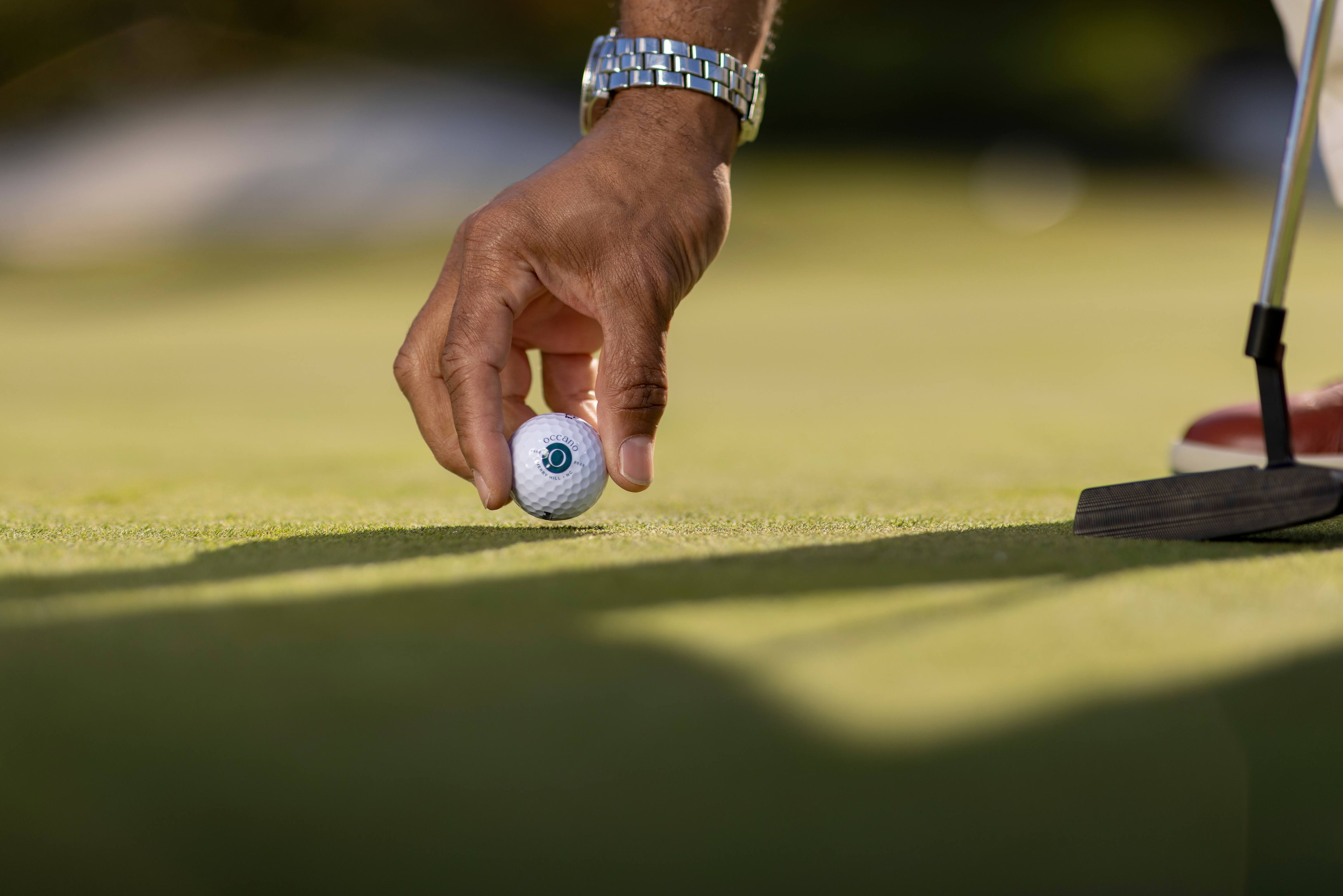 Golfer placing ball on green